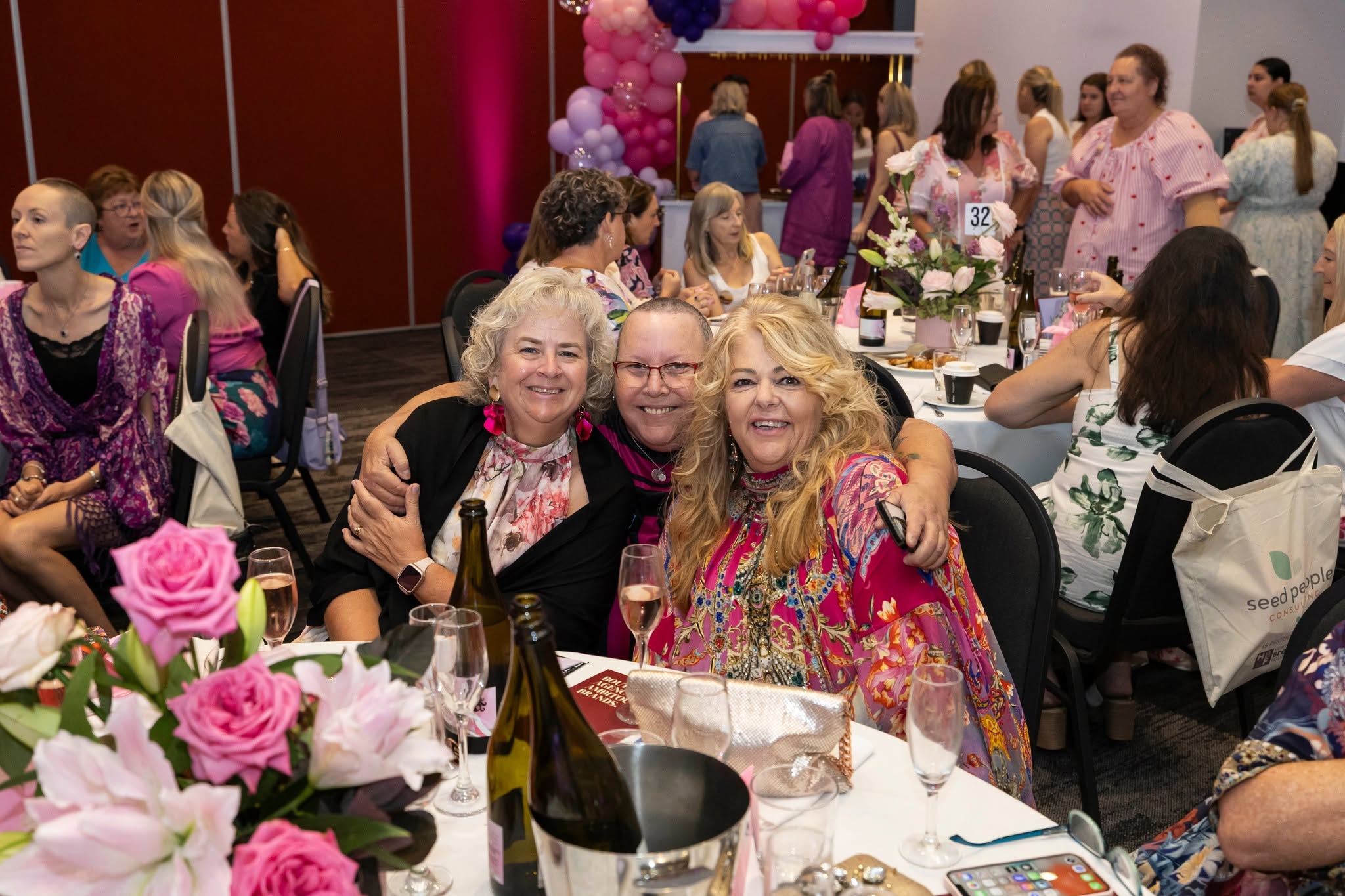 Three guests smiling together at HBCF Bubbly Breakfast 2026