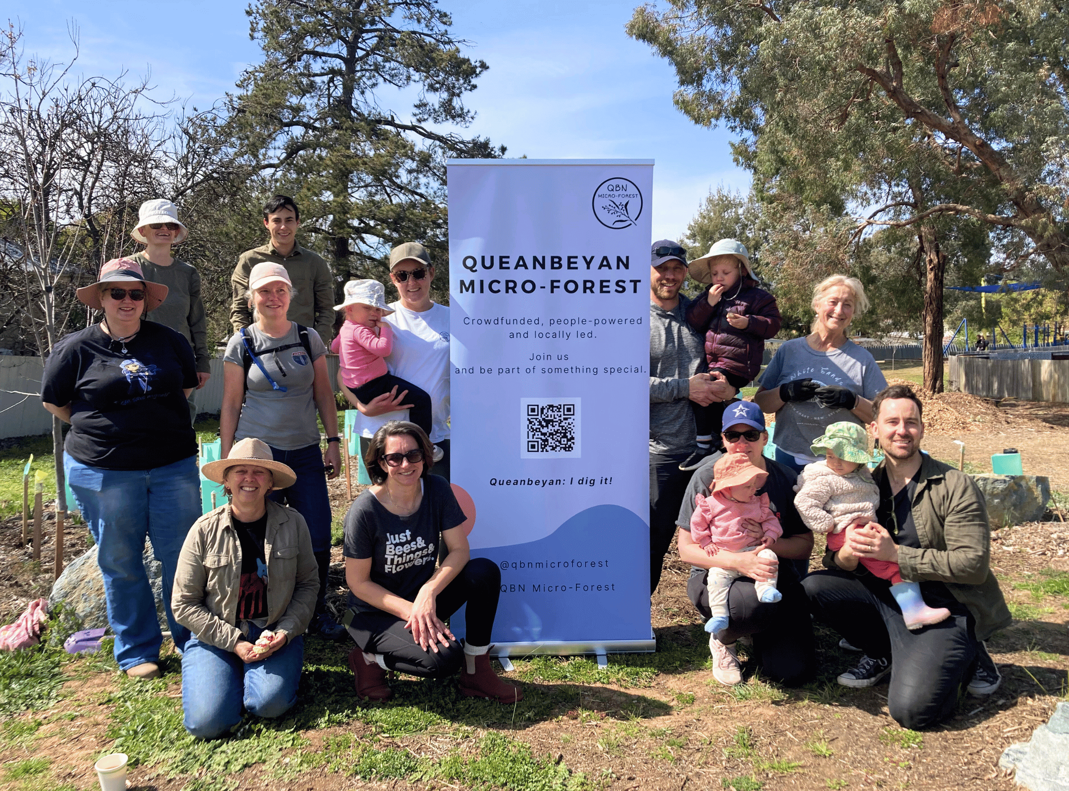 People gathered around a pop up banner in a microforest